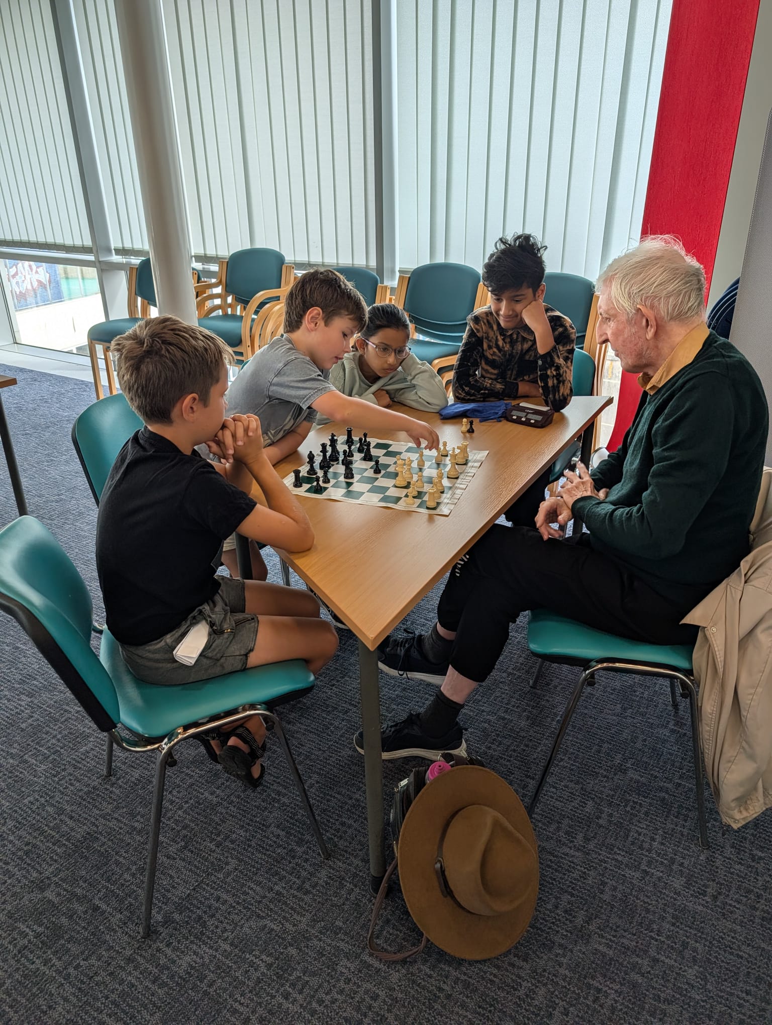 Juniors gathered round a board with a coach at Bournemouth Junior Chess Club