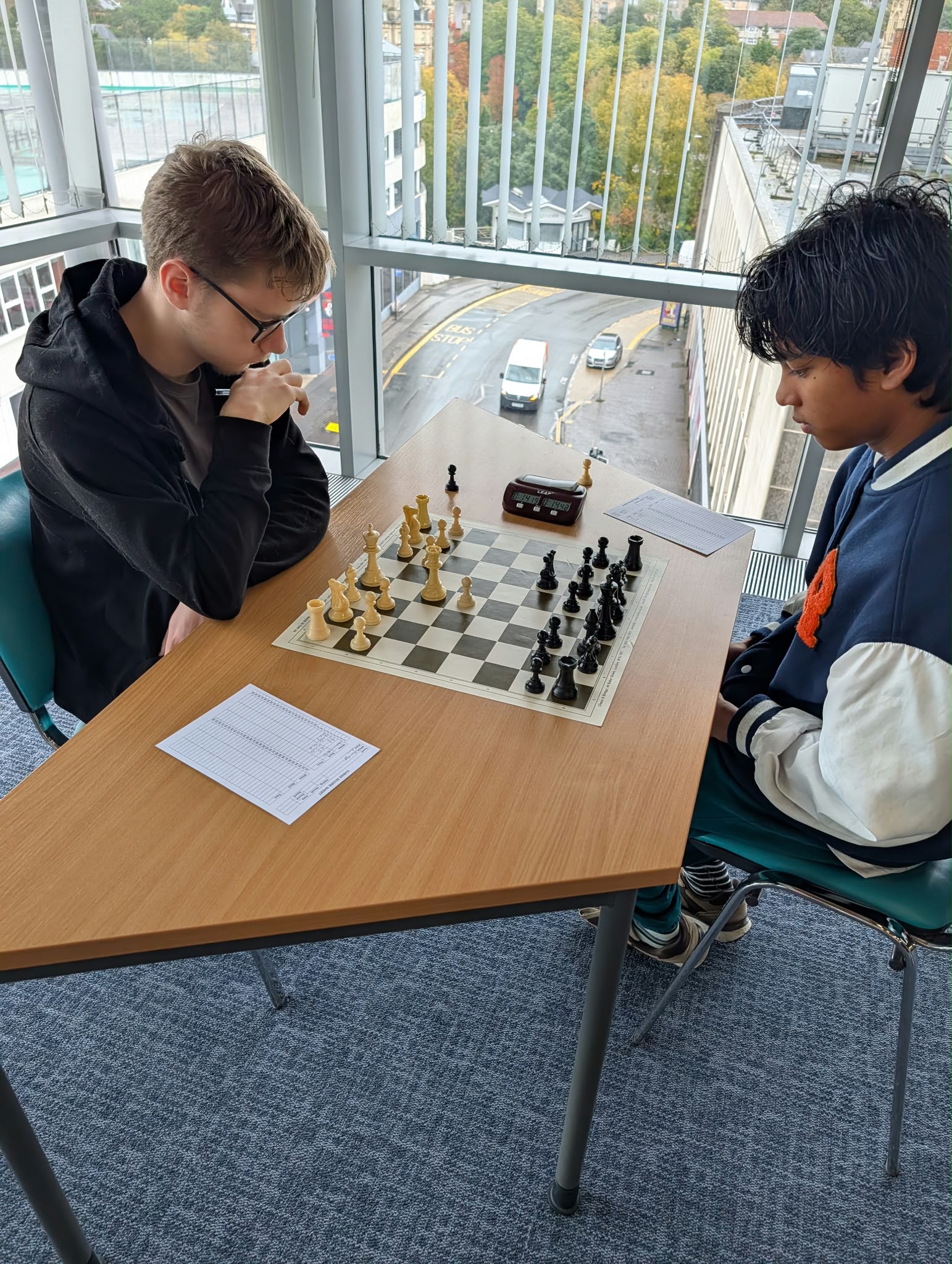 Two players notating their game by the window